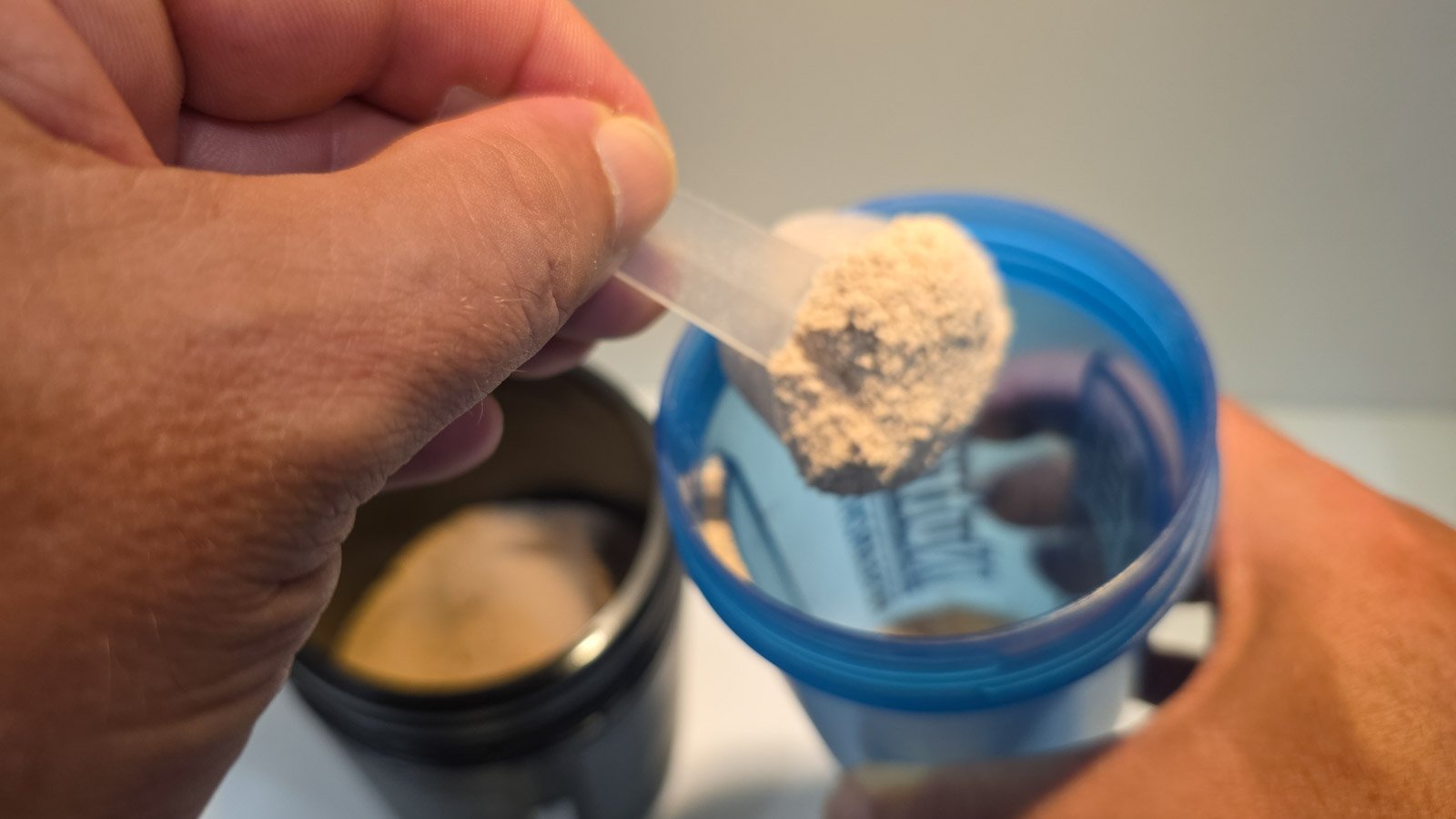 Pouring whey protein into a shaker bottle after a workout